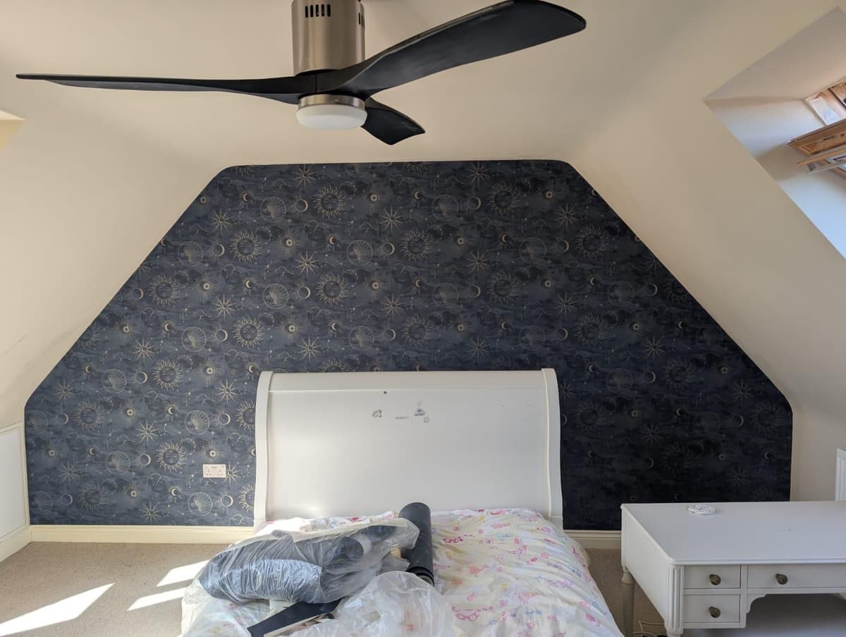 Loft bedroom with celestial wallpaper feature wall