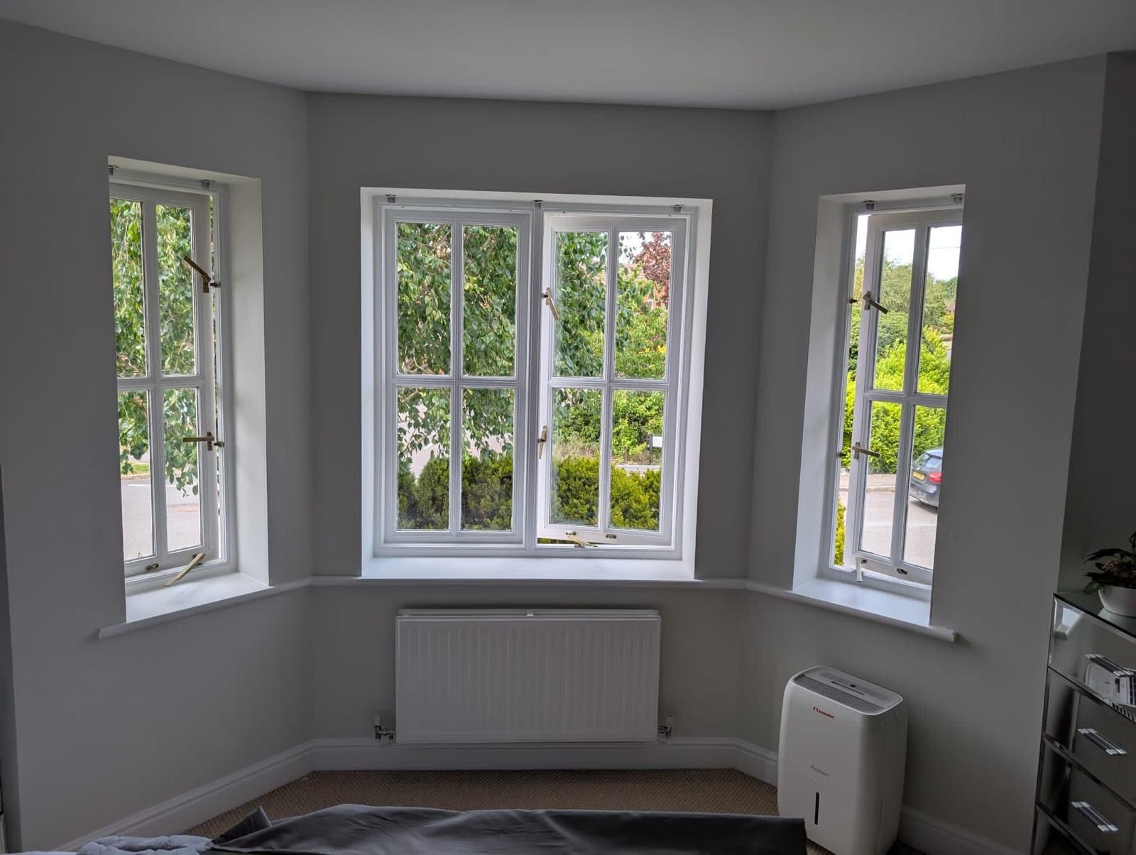 Bedroom painted grey with white bay window frames