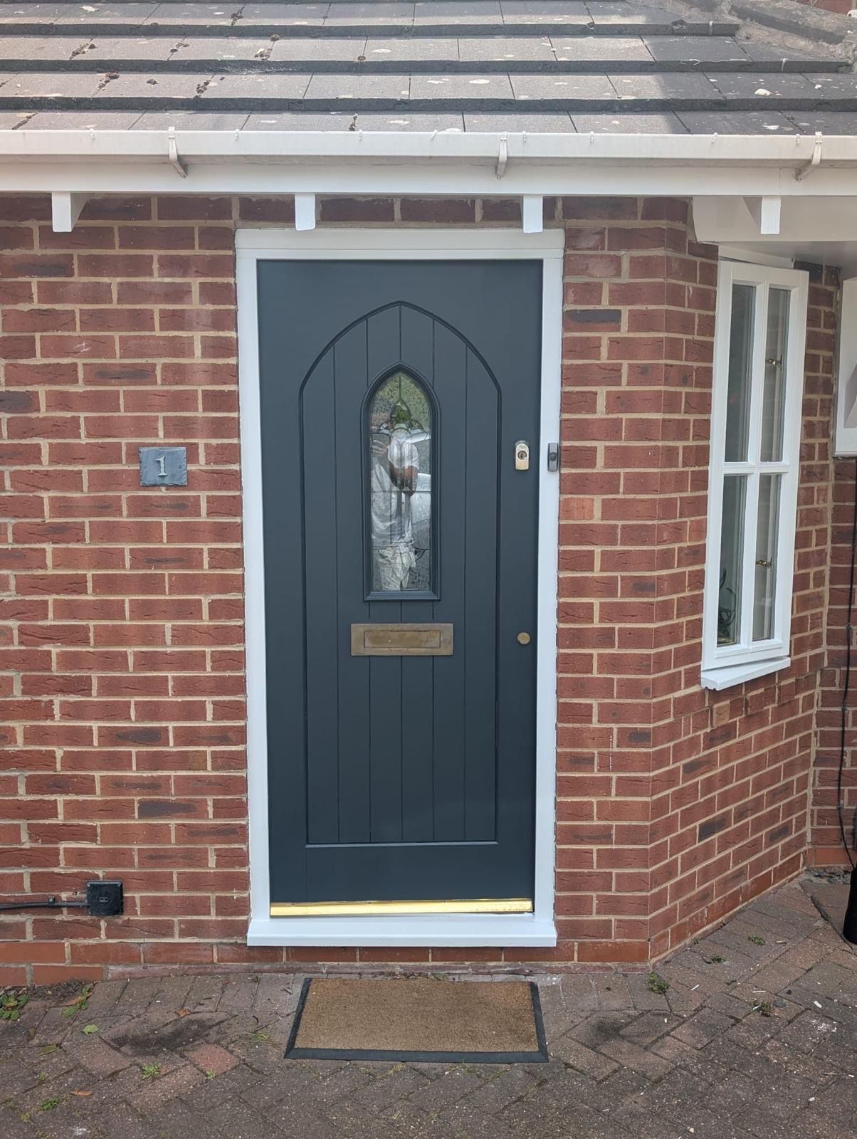 Dark grey painted front door with white frame and brass fittings