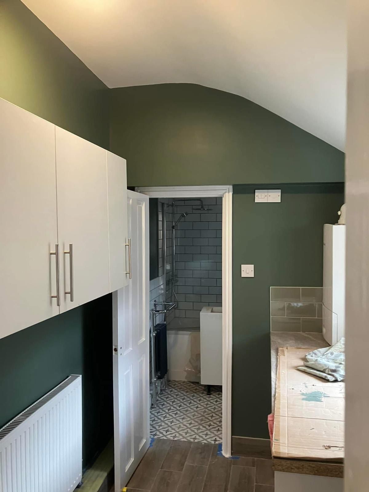 Kitchen utility painted dark green with white cabinets and arched ceiling