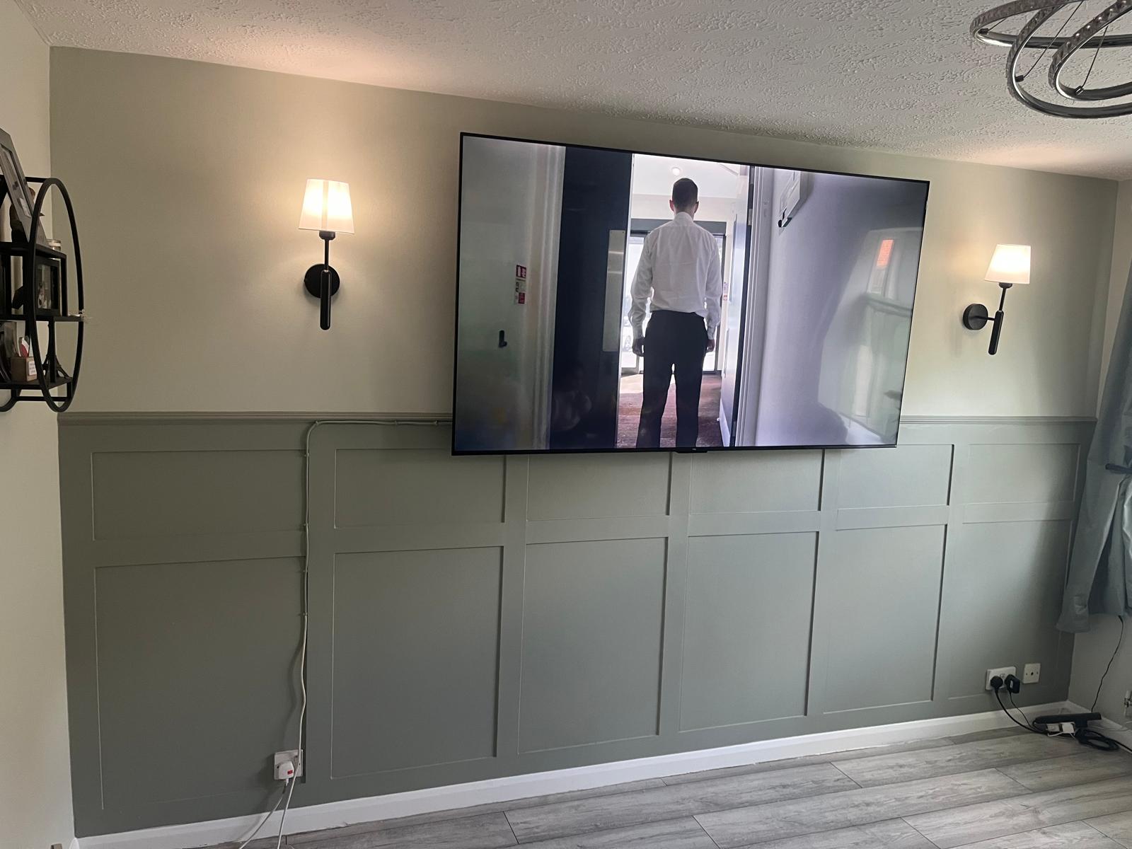 Finished sage green shaker panelling with wall lights and TV